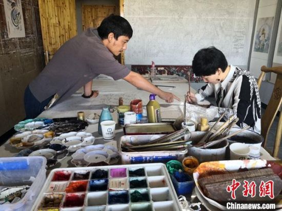 圖為2020年8月下旬，敦煌“80后”畫家張杰龍(左)在為云南麗江“學(xué)生”莫北講解敦煌壁畫的繪畫技巧?！●T志軍 攝