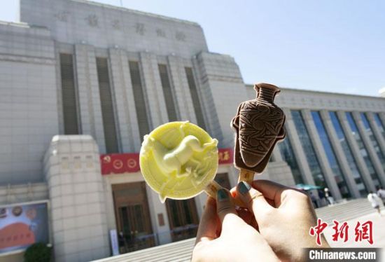 2021年7月30日，游客手拿“銅奔馬”“彩陶瓶”造型的雪糕，在甘肅省博物館前拍照打卡?！「哒?攝
