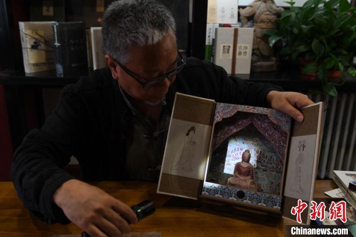 圖為讀者出版集團(tuán)讀者晉林工作室獨(dú)立出品人徐晉林，展示互動(dòng)性強(qiáng)的敦煌題材手工書。(資料圖) 楊艷敏 攝