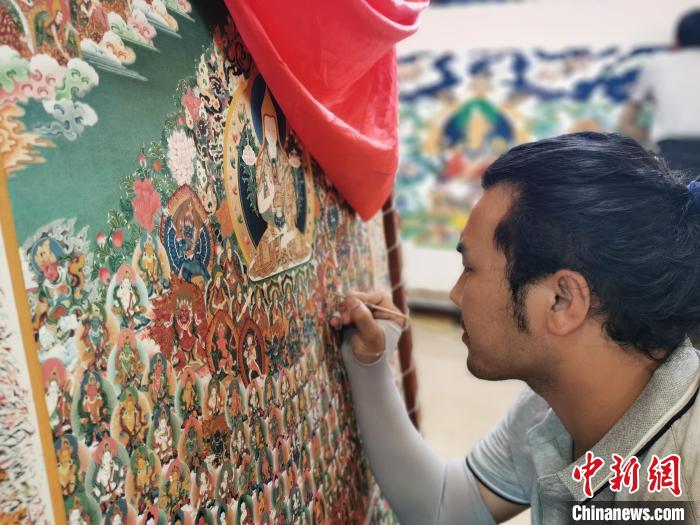 圖為更登才讓的徒弟繪畫唐卡?！?zhí)砀?攝